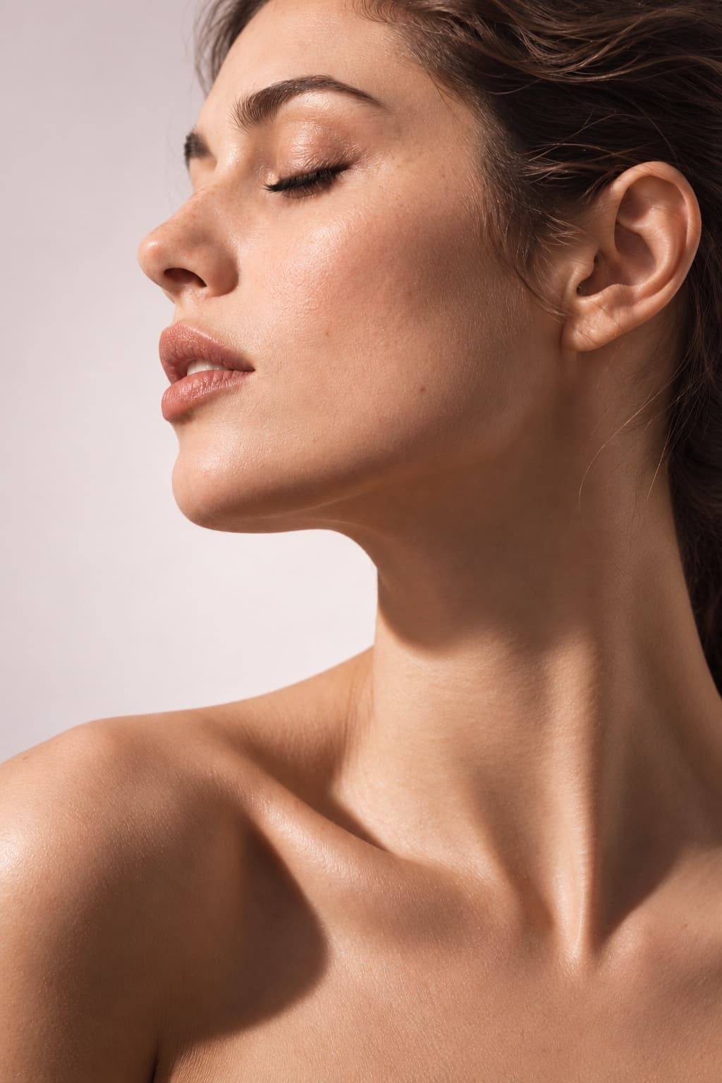Profile of a woman with her eyes closed, the skin of her face, neck and décolleté smooth
